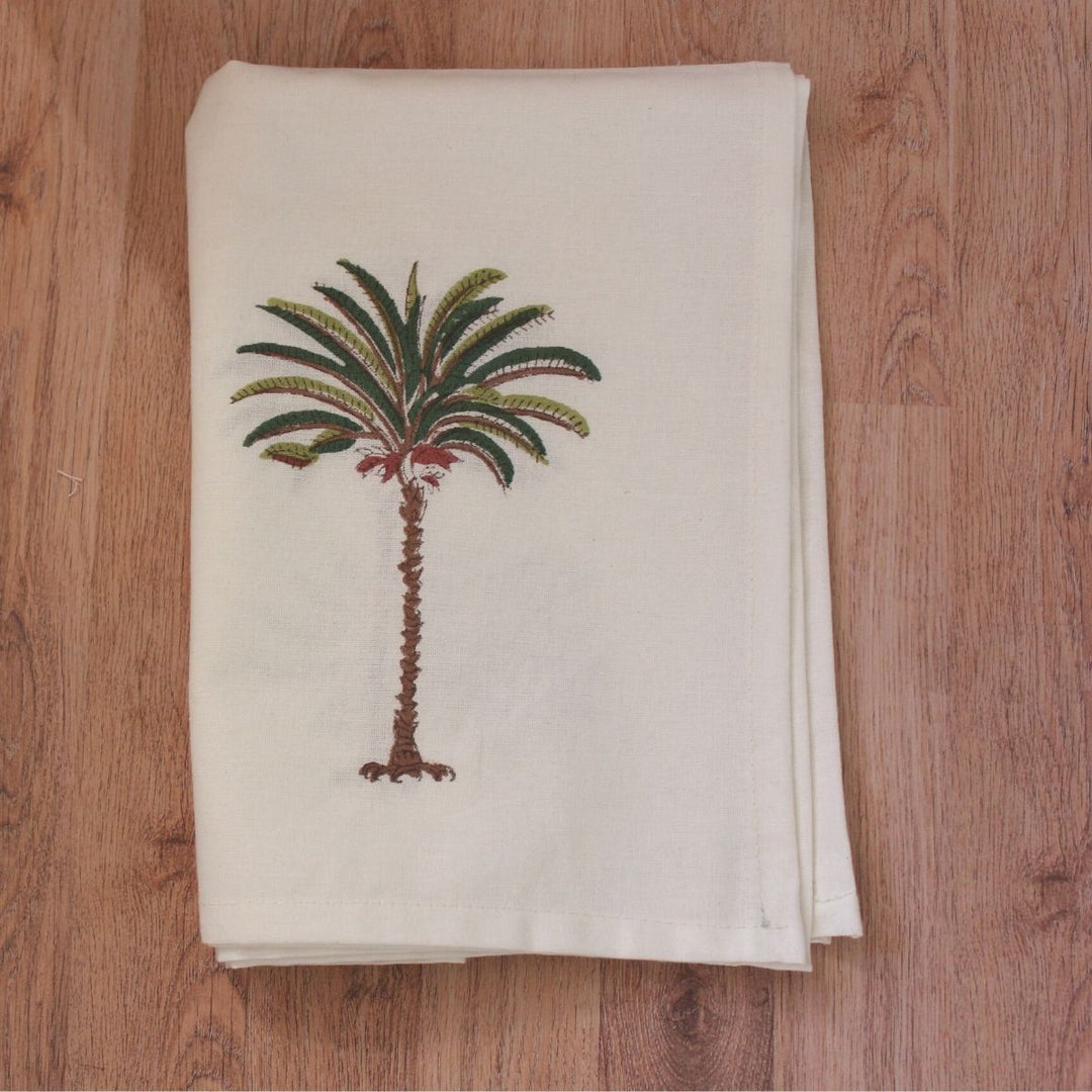 A hand block print napkin set with a green brown palm pattern on cotton fabric, laid out on a table.
