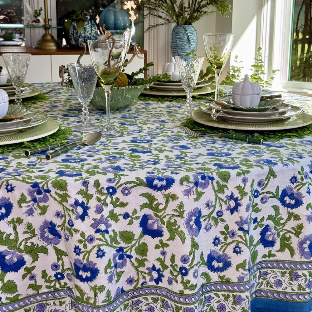 Blue and green floral hand block-printed round tablecloth styled with layered blue and green plates for a festive fall gathering.