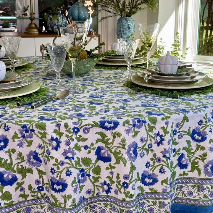 Blue and green floral hand block-printed round tablecloth styled with layered blue and green plates for a festive fall gathering.