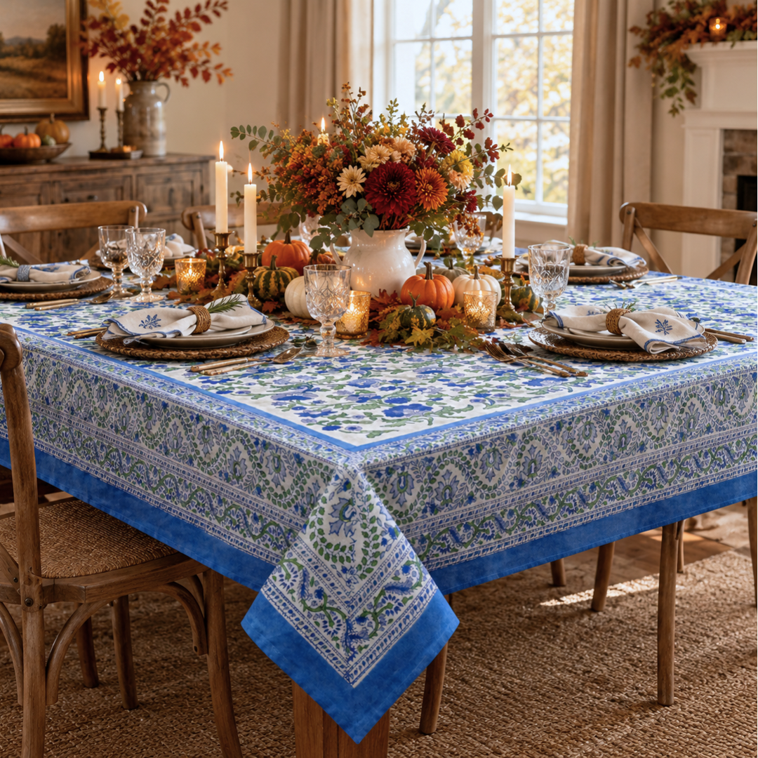 Blue and green hand block printed floral tablecloth dressed on a dining table for Thanksgiving family dinner with seasonal floral centrepiece, wine glasses and accented dinnerware