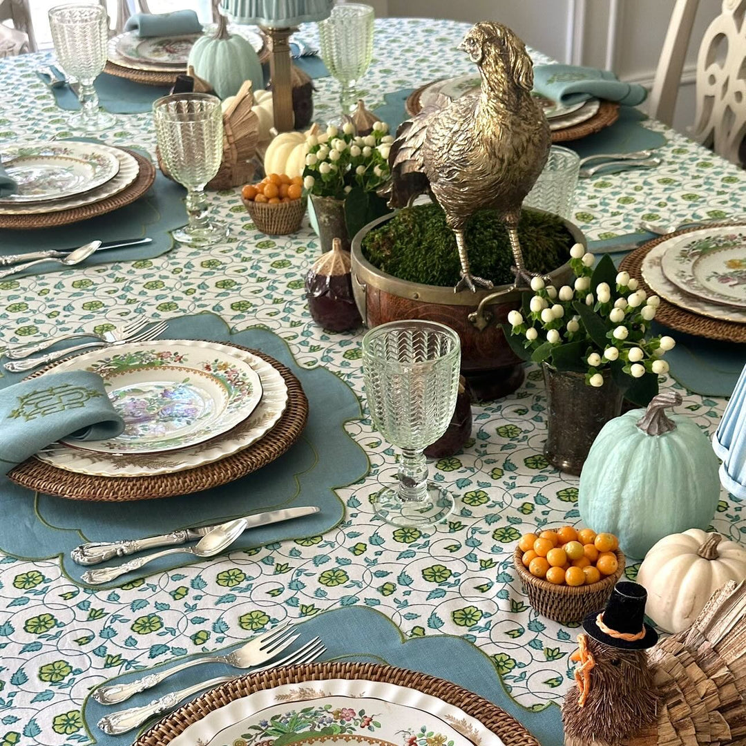Block printed blue green floral tablecloth set for a Thanksgiving dinner with family and friends with seasonal decor accents and elegant china dishes.