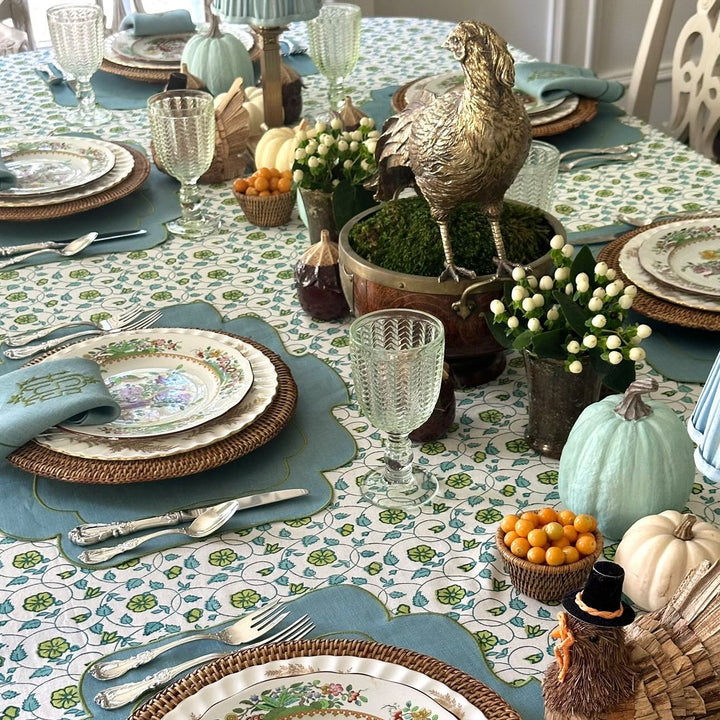 Block printed blue green floral tablecloth set for a Thanksgiving dinner with family and friends with seasonal decor accents and elegant china dishes.