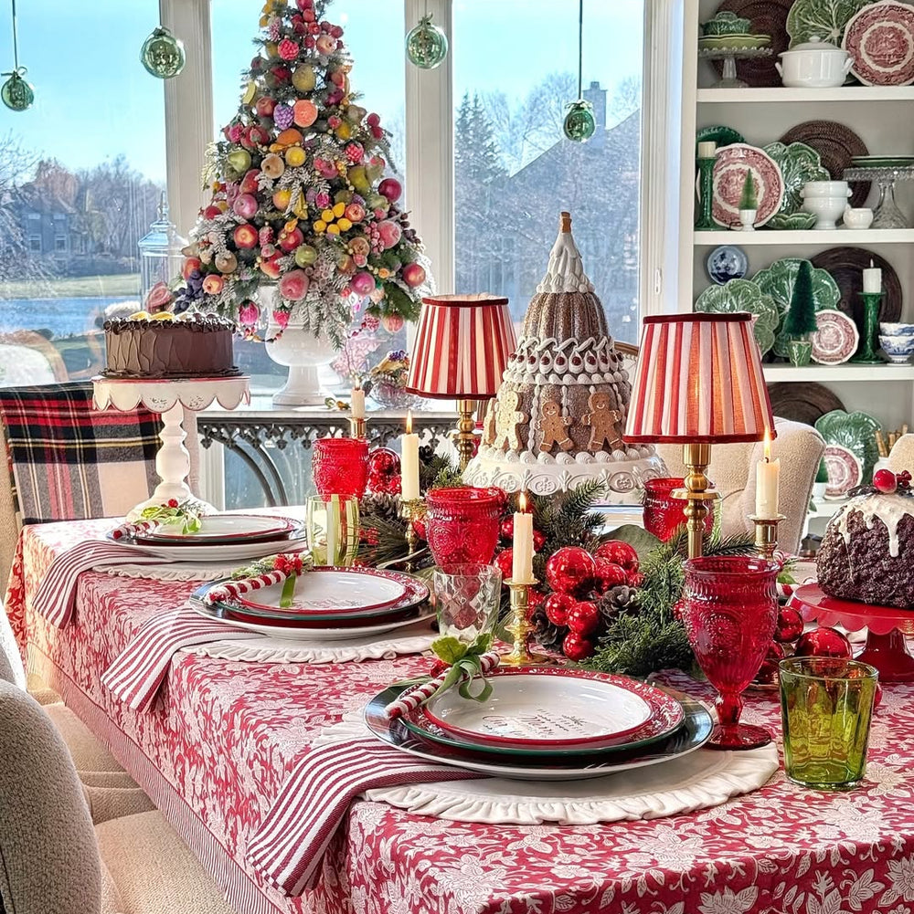 Decorative Christmas table setting with red and white tablecloth, festive decorations, and a Christmas tree.