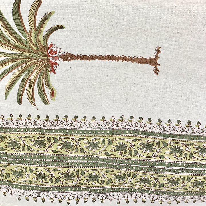 Decorative fabric with palm tree design and intricate floral border pattern on a white cotton background