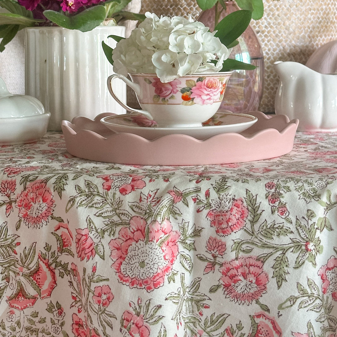 Detail shot of pink floral round tablecloth set for a small fall gathering. Hand block printed on premium cotton with a striped border edging.