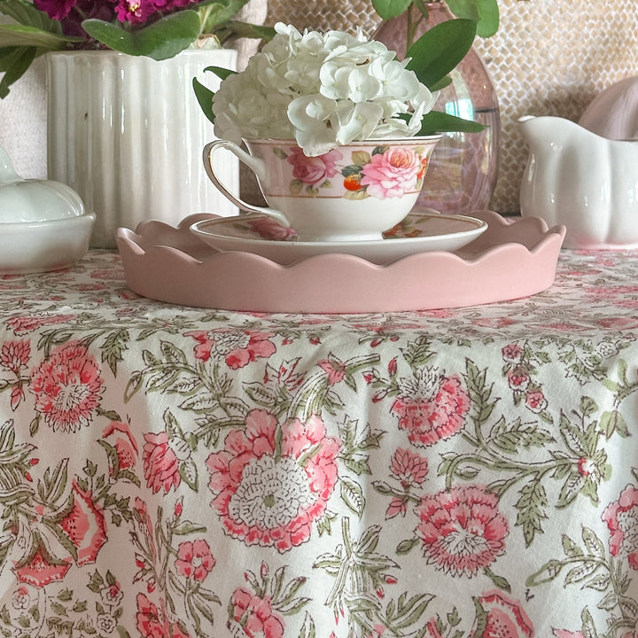 Detail shot of pink floral round tablecloth set for a small fall gathering. Hand block printed on premium cotton with a striped border edging.