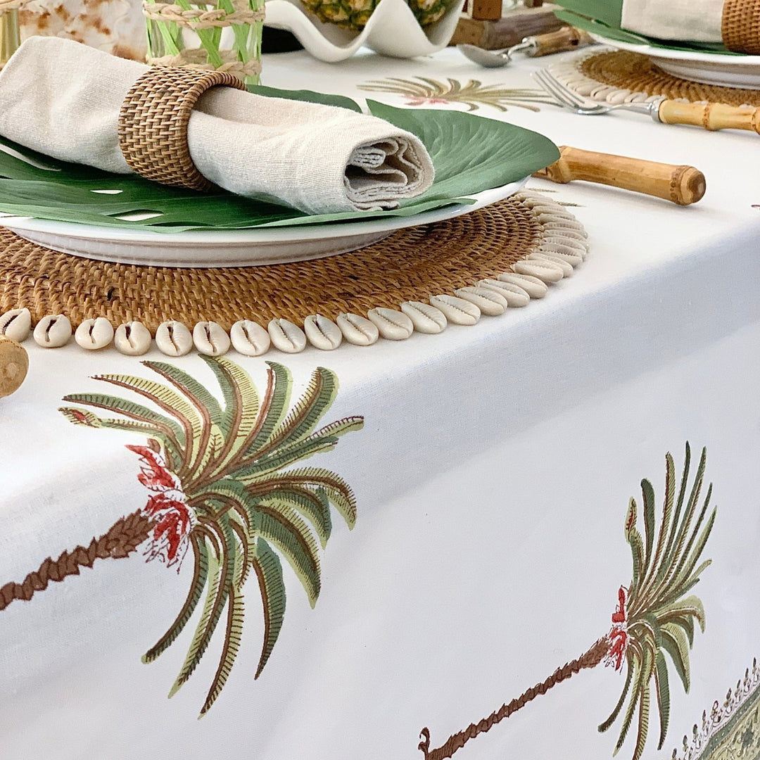 Table setting with palm tree design tablecloth, plates, and decorative elements.