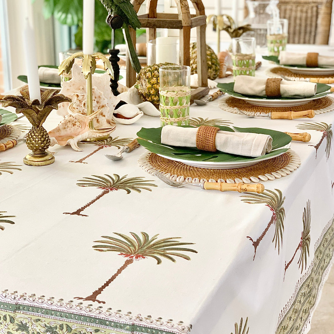 Table setting with palm tree design tablecloth, green plates, and decorative elements.