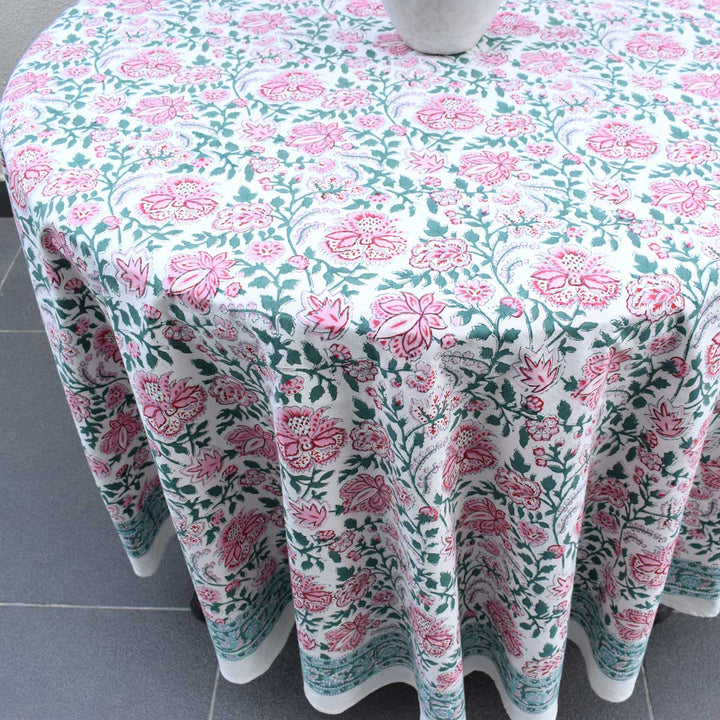 Angle shot of  pink green floral pattern block printed by hand on cotton round table cover by artisans in jaipur rajasthan