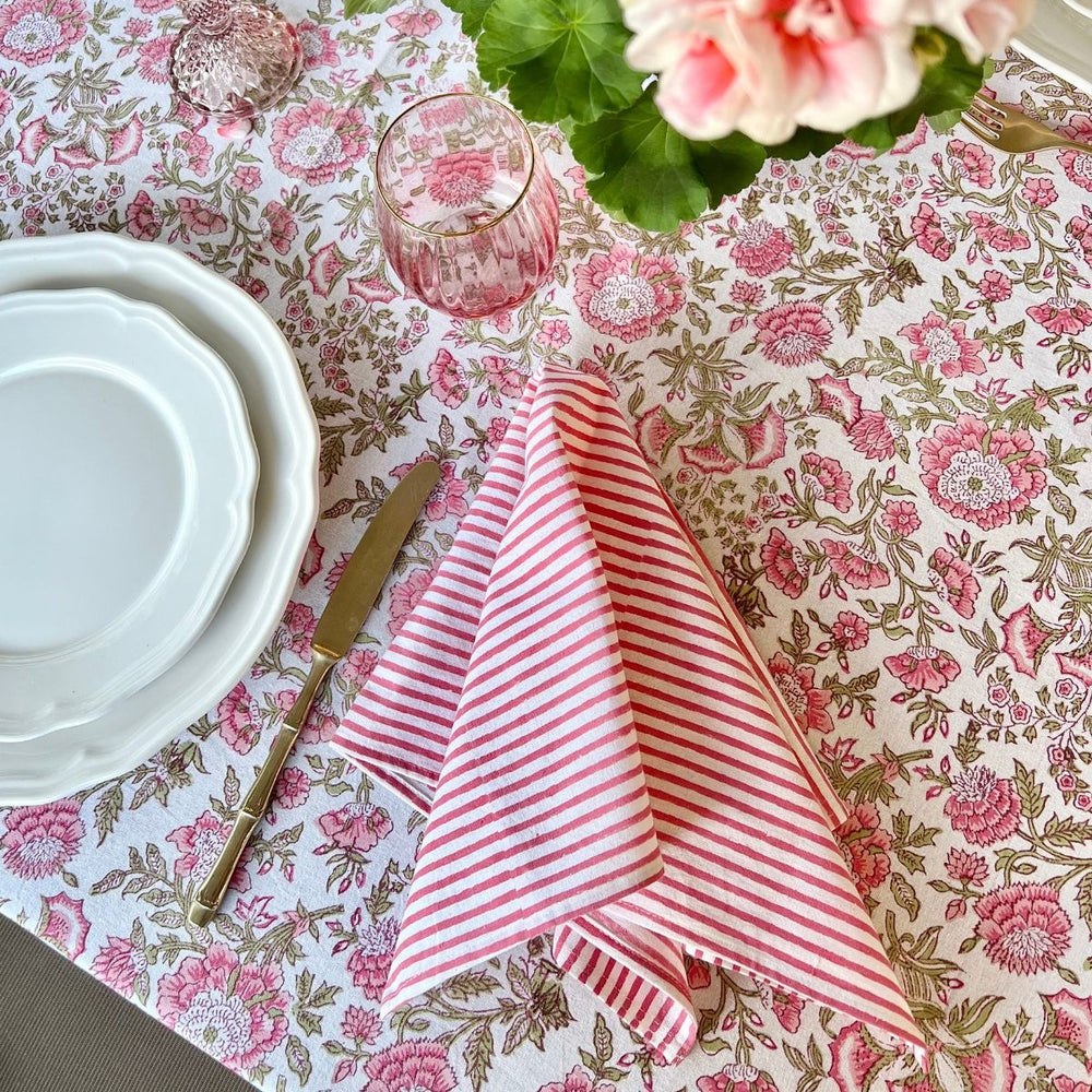Pink striped cotton napkin folded casually and laid on a floral tablecloth
