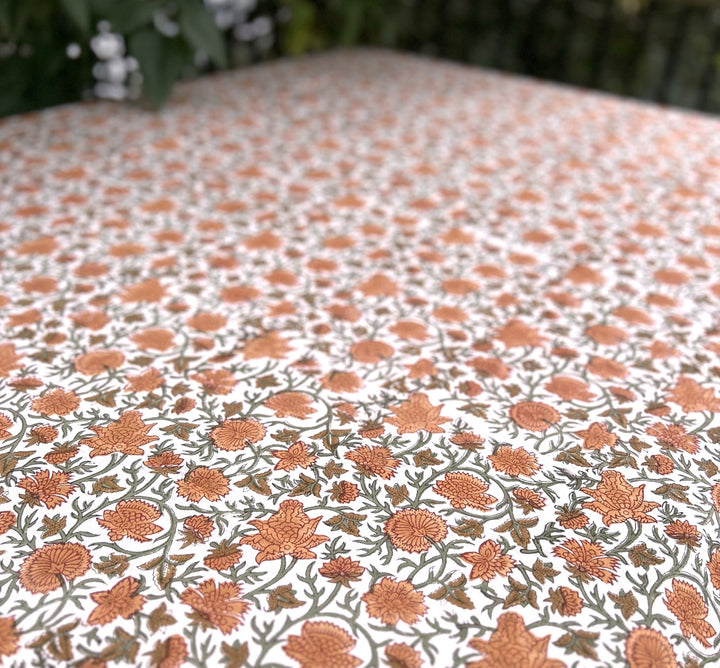 Detail of the warm terracotta floral hand block printed pattern on a rectangular fall tablecloth in 70 x 108 inches, ideal for a harvest table that seats eight