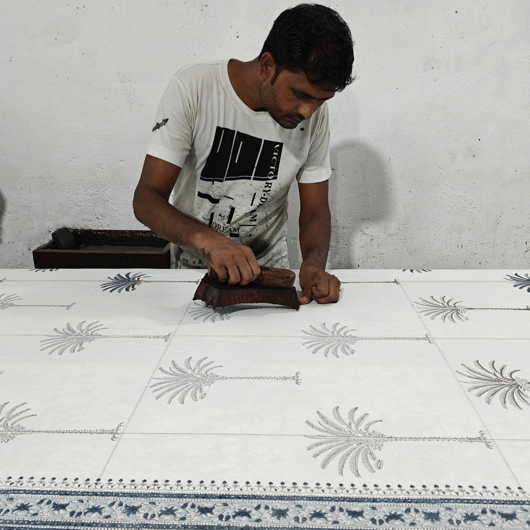 Artisan block printing palm motifs on pure cotton fabric for small batch production of table linens