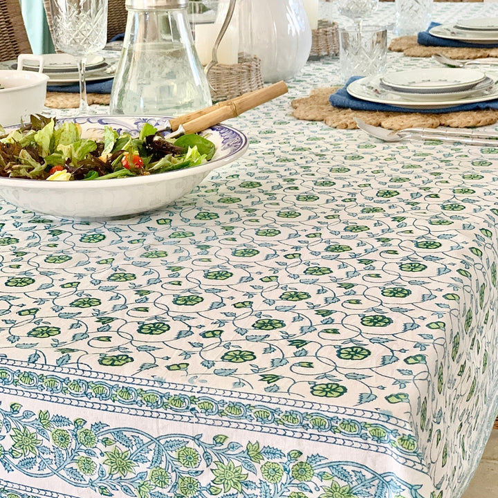 blue and green block print floral tablecloth displayed on a large rectangular tablecloth with salad, glass jugs and white dishes for casual dining