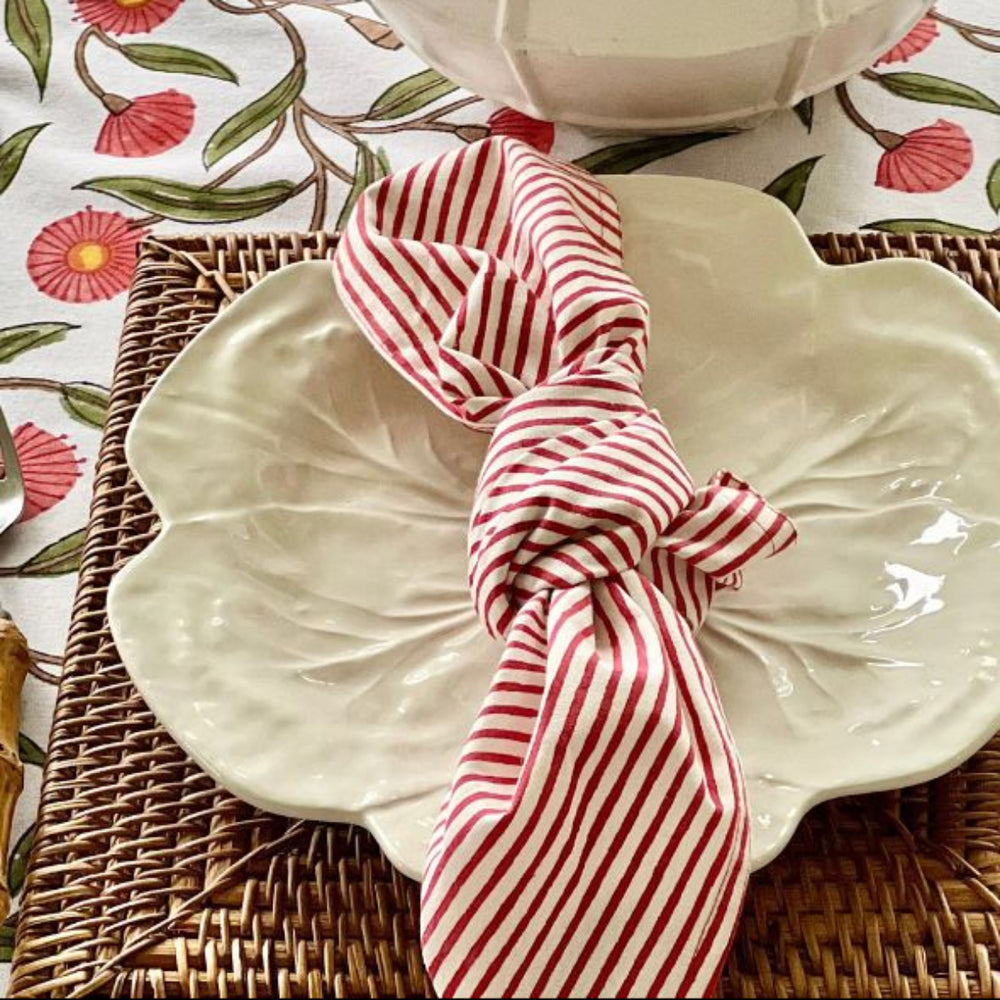 White plate with a red and white striped napkin on a floral tablecloth